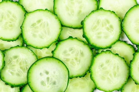 Multiple slices of cucumber with a white background peeking through