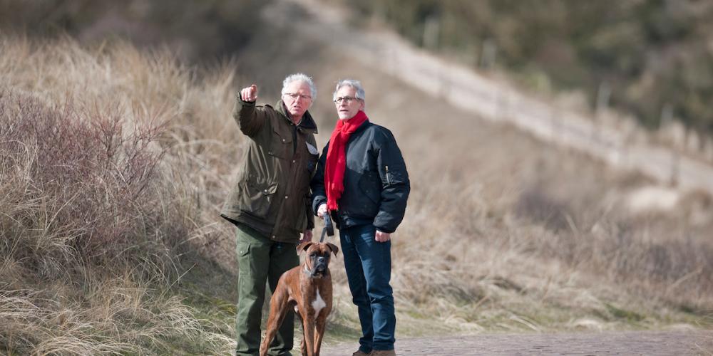 Boswachter Jan wijst bezoeker met hond de weg